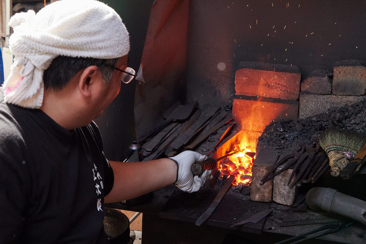 A Japanese smith heating a blade in the forge
